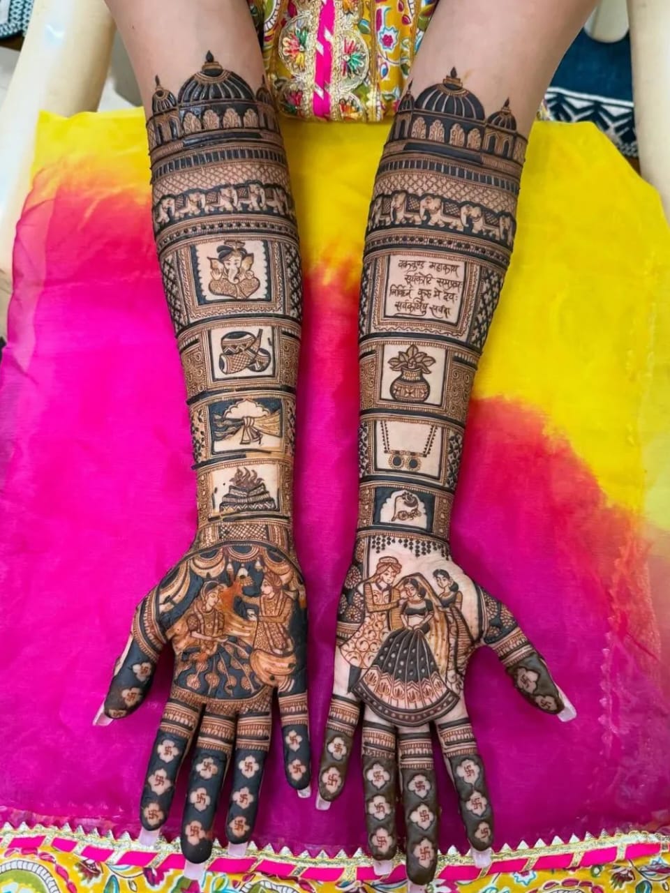 Full-hand bridal mehndi with Ganesha and dulha-dulhan motifs